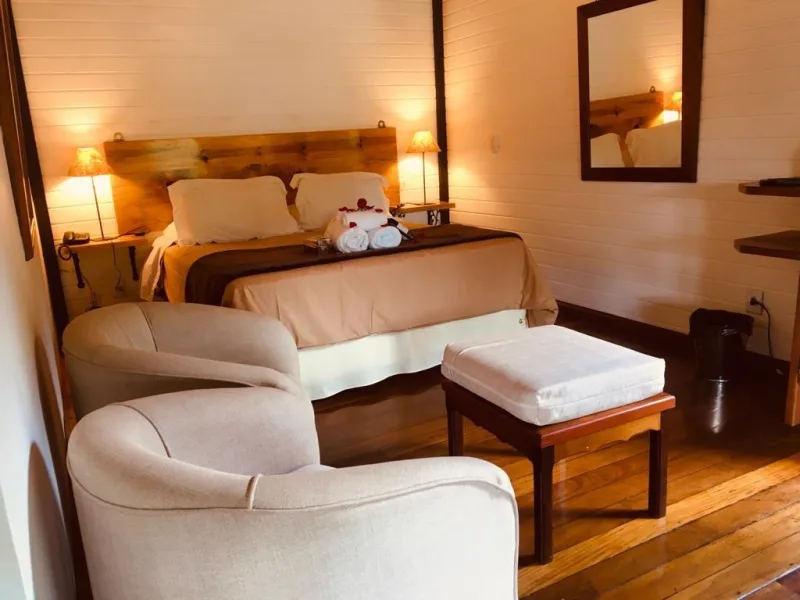 Quarto com cama e poltronas no Chalé 01